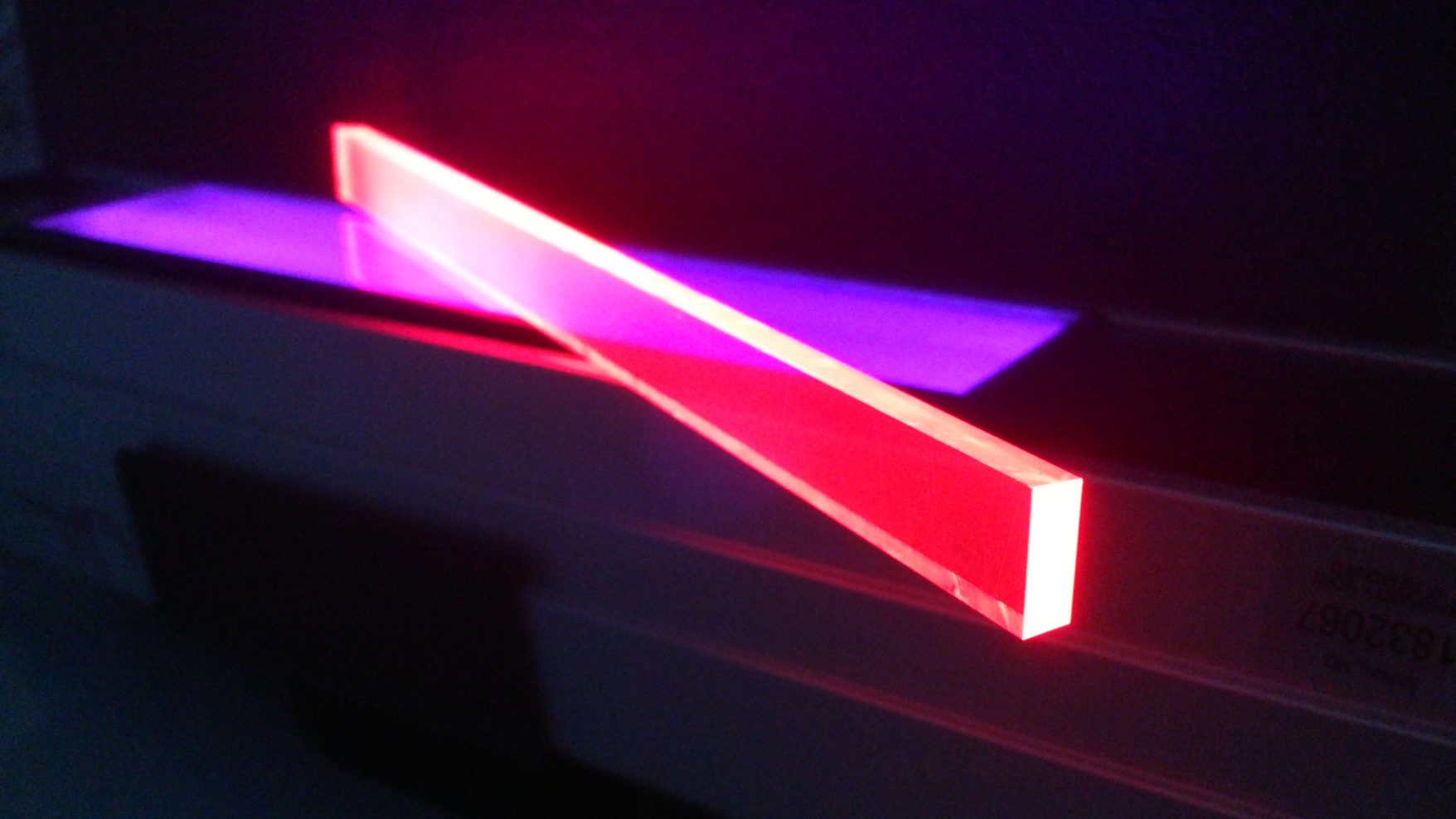 Abstract image of glowing acrylic pieces in red and purple contrasting against a black background