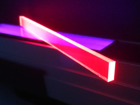 Abstract image of glowing acrylic pieces in red and purple contrasting against a black background