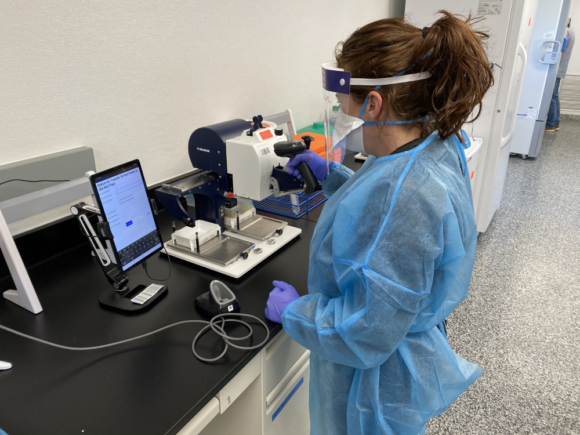 Photograph of a lab worker in full PPE working on a COVID-19 testing lab