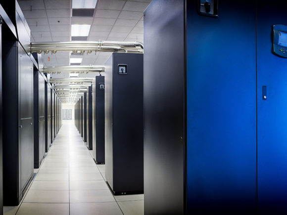 Photograph of the Blue Waters supercomputer and walkway between cabinet rows with cooling pipes above