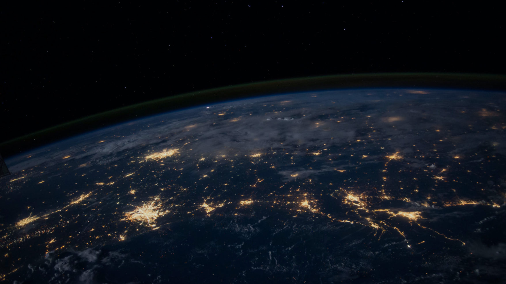Night photograph of the Earth from space with lights indicating larger populated areas of the globe