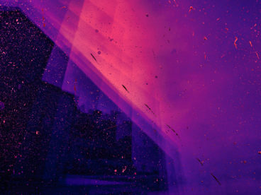 Abstract angular shapes in gradients of purple, pink, and blue with pink specks scattered throughout the image