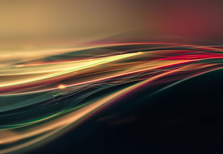 Abstract and stylized image of smooth motion lines in yellow, red, green, and teal on a dark black to yellow and red gradient background