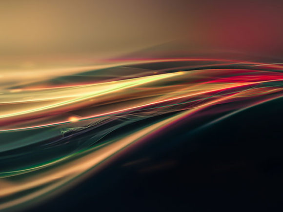 Abstract and stylized image of smooth motion lines in yellow, red, green, and teal on a dark black to yellow and red gradient background