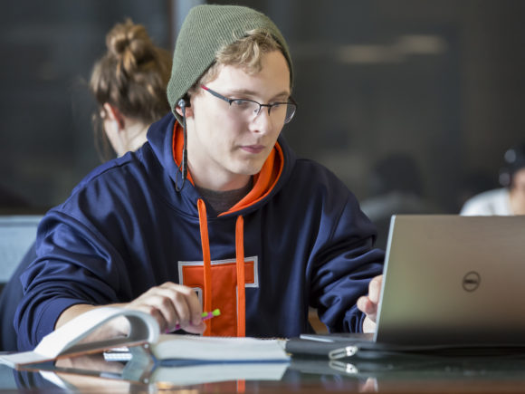 Photograph of a male student studying in front of a laptop in the Electrical and Computer Engineering building