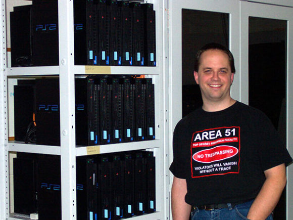 2003 photograph of Craig Steffen standing next to a cluster of Playstation 2 consoles at NCSA