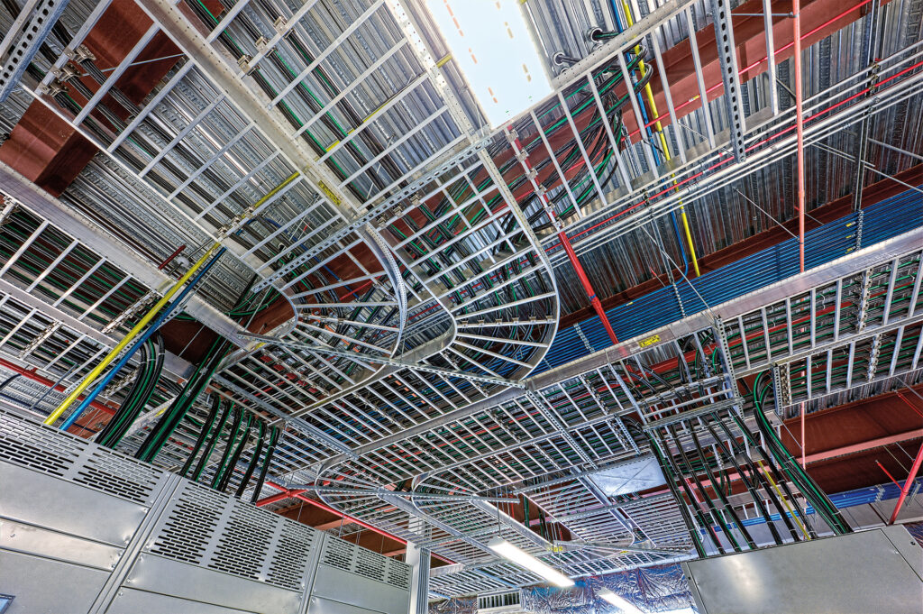 Photograph of cable and electrical management at the National Petascale Computing Facility. Cables are seen running along the ceiling infrastructure in a neat and orderly fashion.