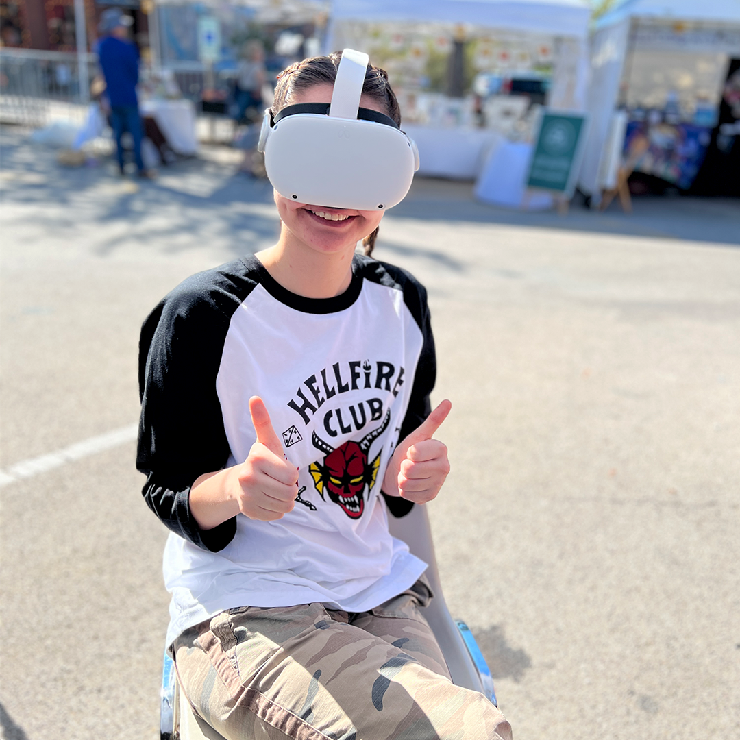 A person wearing a VR headset smiling and giving two thumbs up.