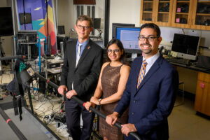 A research team poses for a photo gripping a handrail in a lab.