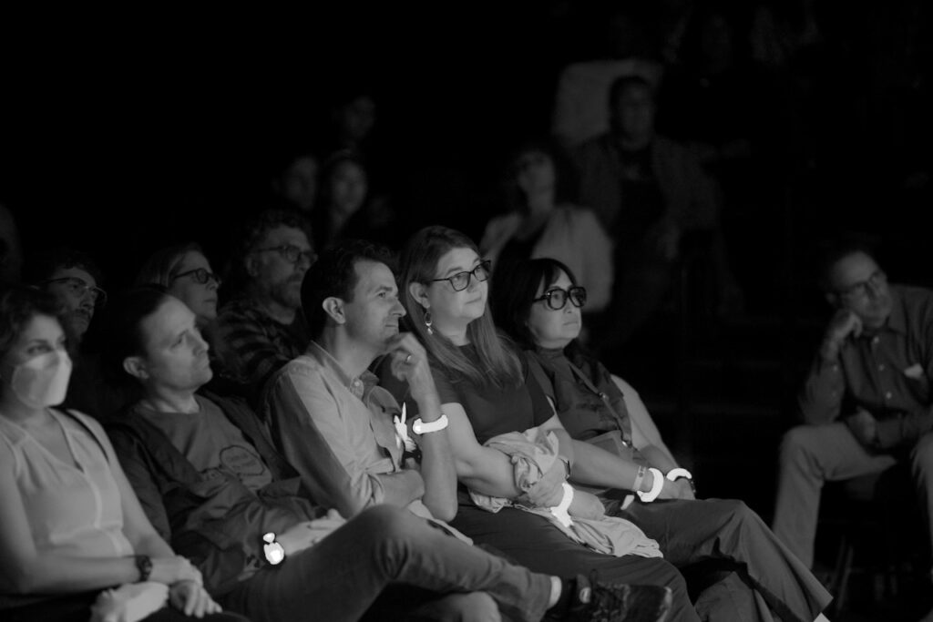 A black and white photo of the audience during the performance. The audience is intensely interested.