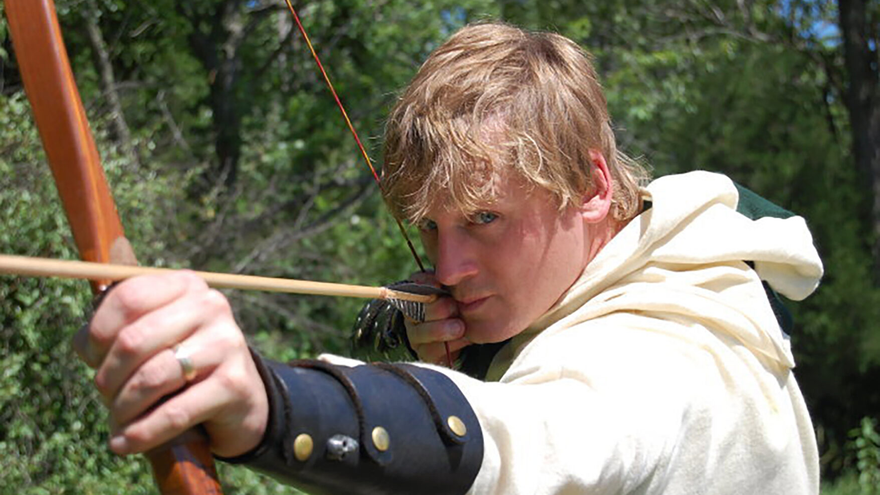 An image of Jeff in an archer costume, holding a bow and arrow, posing as if ready to shoot.