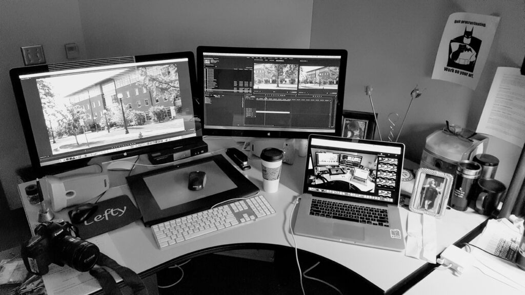 A black and white image of Jeff's workspace. There are several monitors displaying AVL projects.