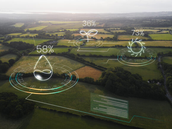 This is an arial photo of farmland, with an overlay of "smart" alerts signifying water levels, light levels, nutrients, etc. It is meant to convey the concept of a smart farm - one monitored by an AI to keep it healthy.