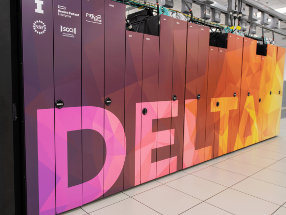 An image of NCSA's Delta supercomputer. The supercomputer is wrapped in a colorful design, the word Delta shifts from violets to oranges and yellows, and triangular color shapes surround it.