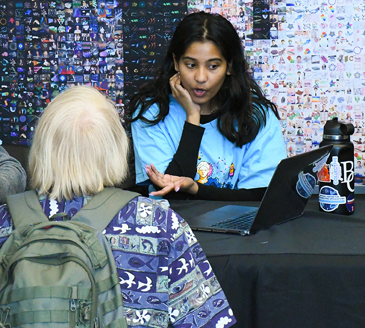 SPIN intern, Sri Nithya Yeragorla, speaks to a visitor at the SPIN table. 