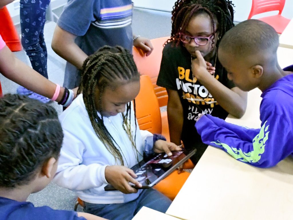 Children in the I-Sci Explorers program practice navigating a rover using a tablet.