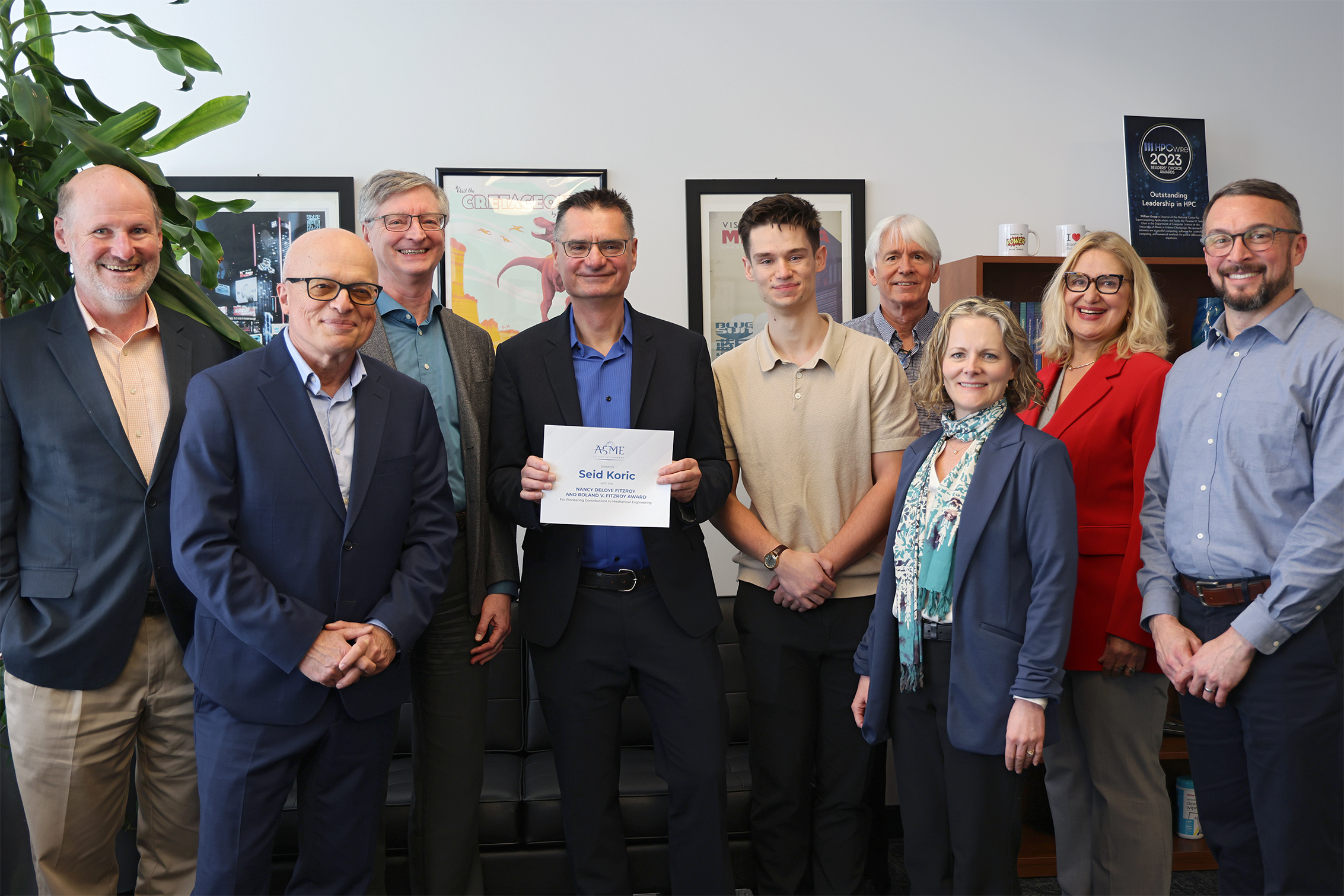 Seid Koric stands with a number of colleagues with his award in his hands.
