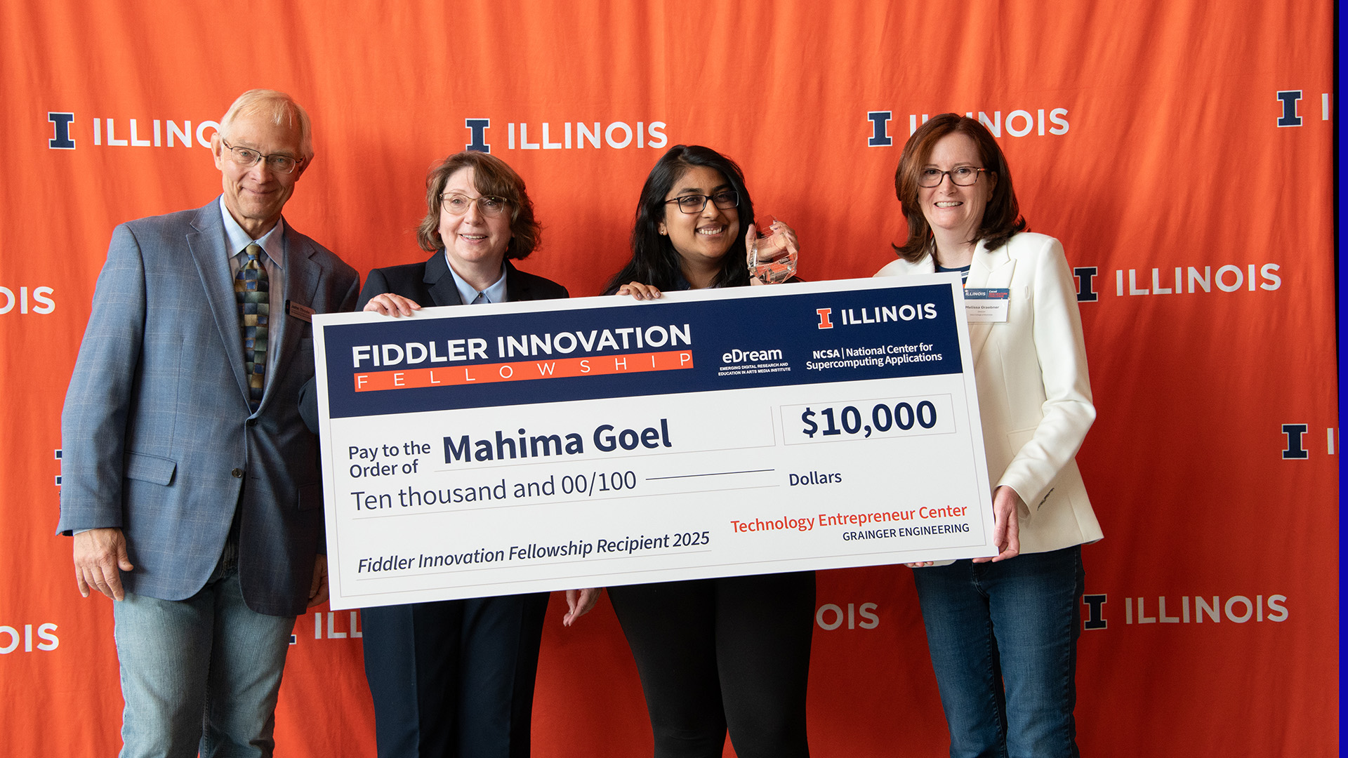 A picture of the award winner accepting an oversized check of the award amount.