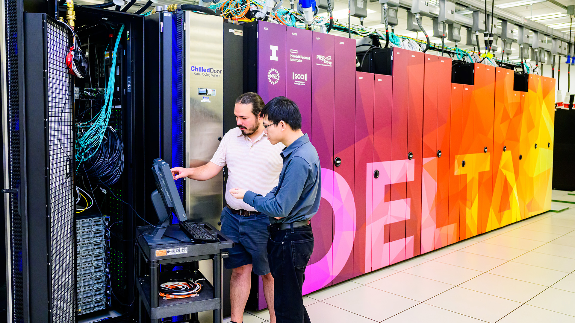 an image of the Delta supercomputer with two staff working on it.