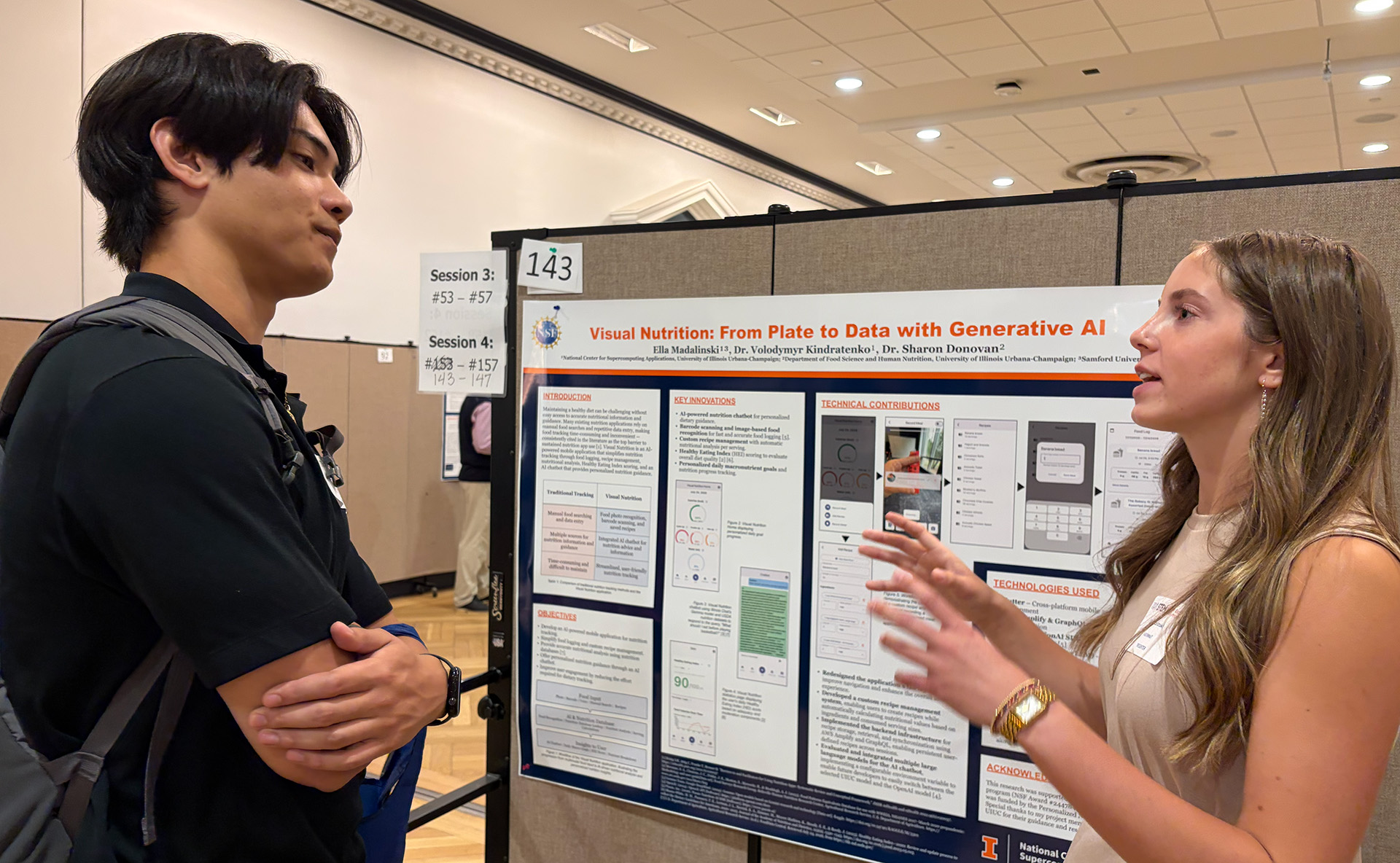 A student shows her poster to a visitor.